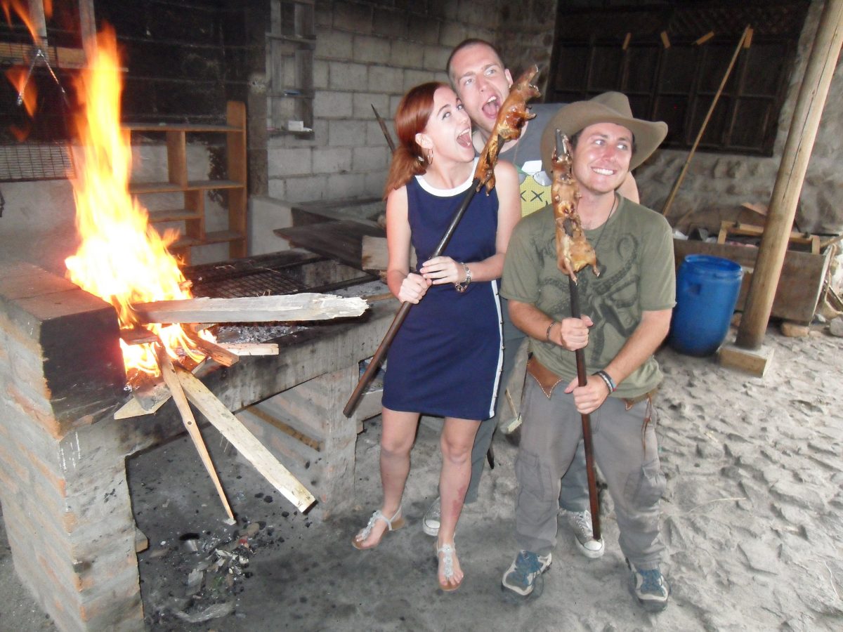 Tourists pose with guinea pigs on a stick while trying the national foods of Ecuador in Quito