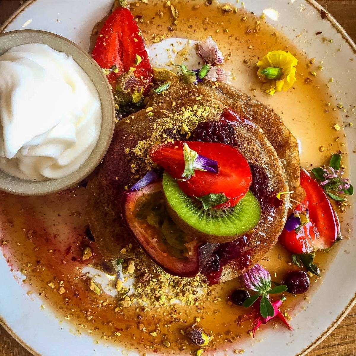 breakfast in Sydney Gourmet pancakes adorned with fresh fruit and edible flowers, showcasing the culinary delights awaiting those moving to Sydney, Australia.