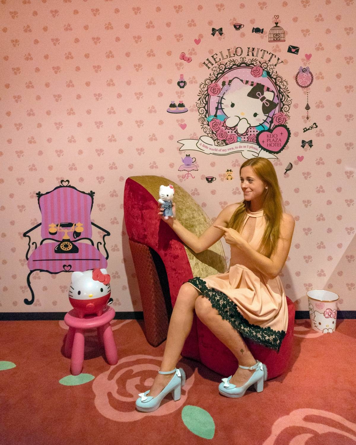 Posing with Hello Kitty decorations in a playful Tokyo theme room.