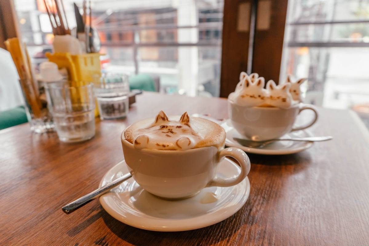 Artistic cat-themed latte art in a cozy 3D Tokyo café.