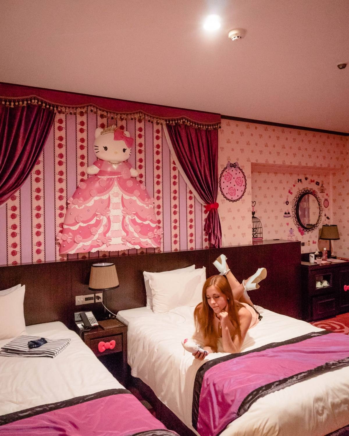 Woman enjoying a stay in a vibrant Hello Kitty-themed hotel room in Tokyo.