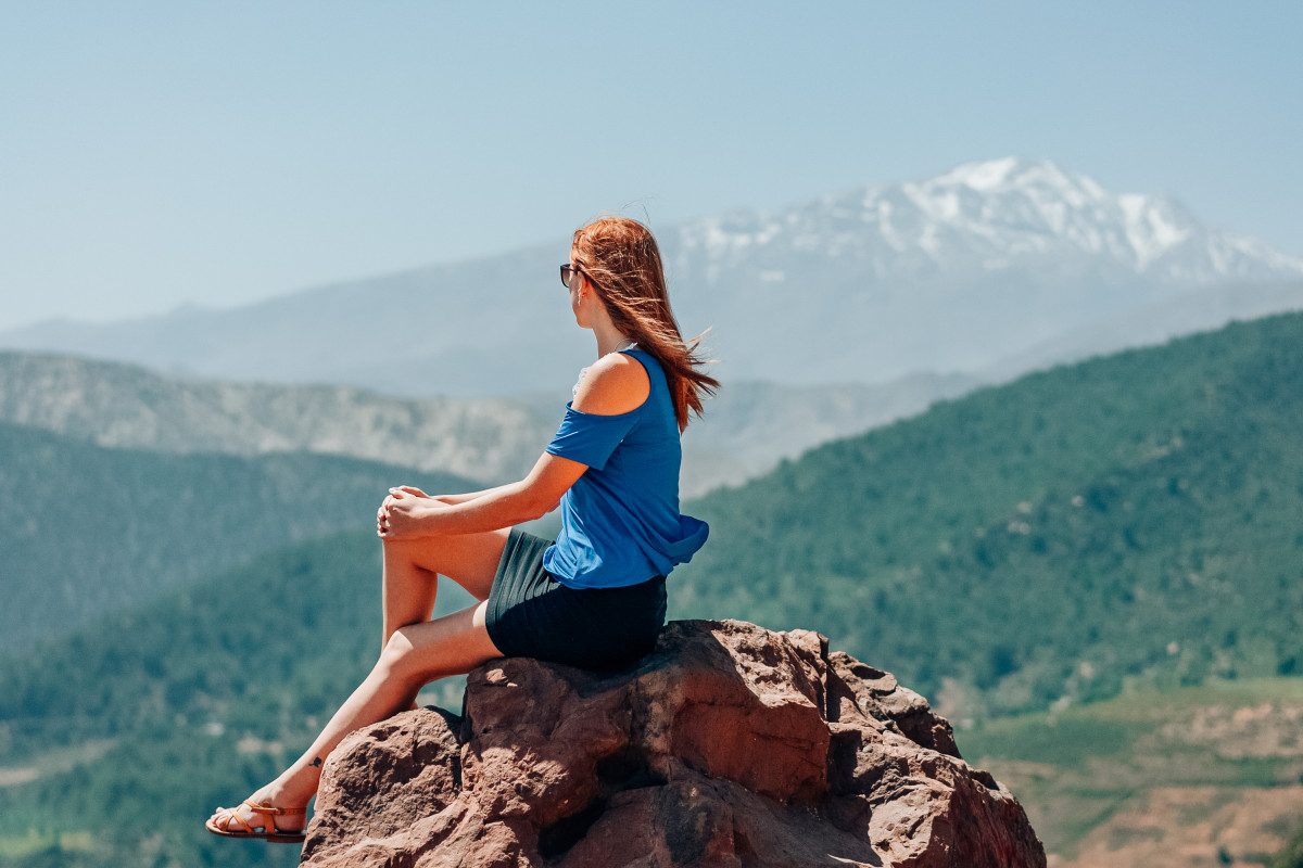 Atlas Mountains A woman contemplating the breathtaking scenery of the Atlas Mountains near Marrakech, a travel tip for those seeking majestic views is to take a balloon tour