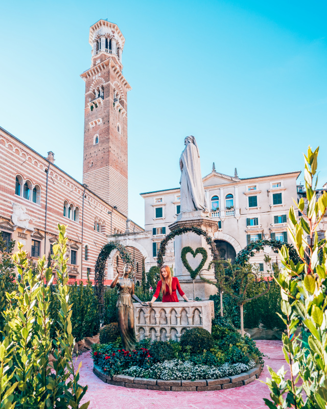 Woman posing in front of the historic Lamberti Tower in Verona, visiting this landmark is a popular thing to do in Verona