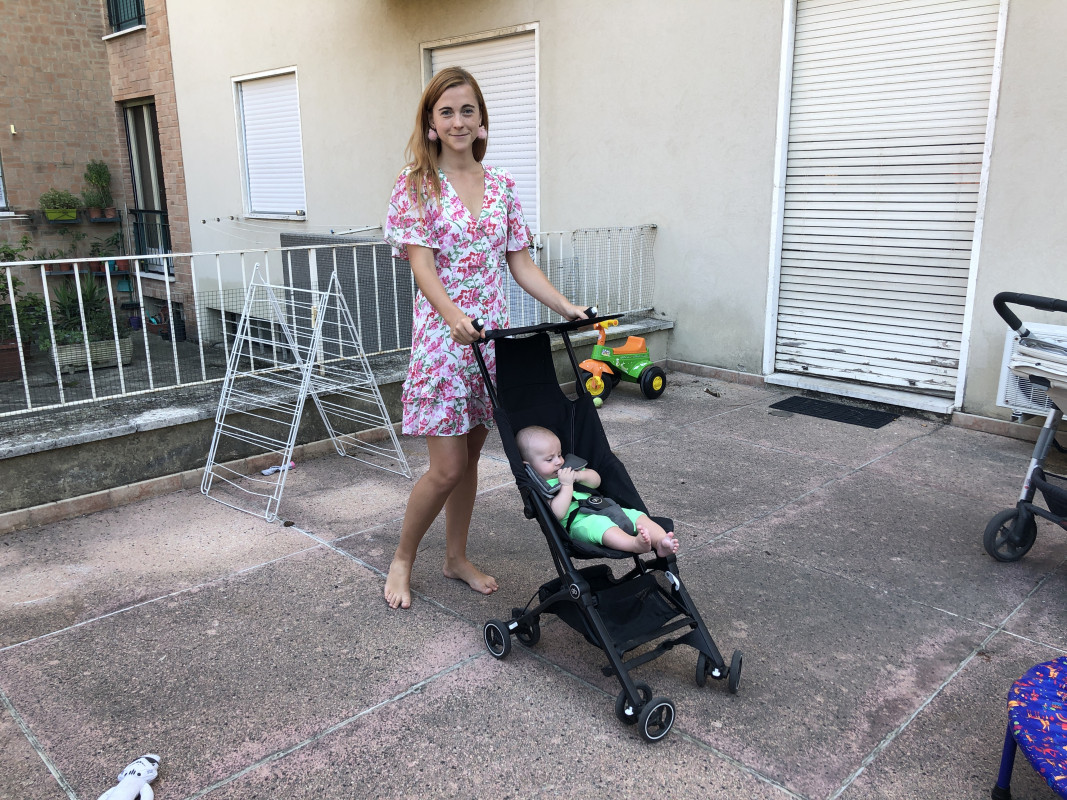 Woman outdoors with a baby in the GB Pockit Stroller, demonstrating the stroller's use in a real-life setting.
