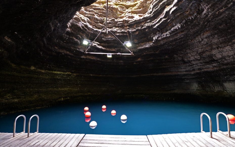 An underground pool at Homestead Crater illuminated by artificial lights, a unique hot spring experience found in Utah.
