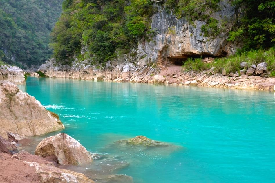 Calm turquoise waters bordered by rugged cliffs at a secluded Mexican canyon, a hidden gem among unique places in Mexico.
