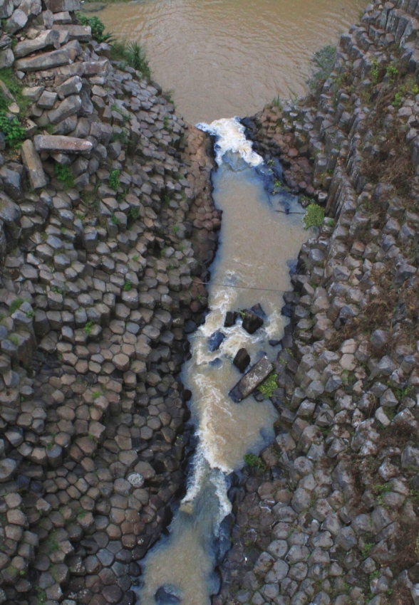 Aerial view of a unique geological formation with a river snaking through it, a hidden natural wonder in Mexico.
