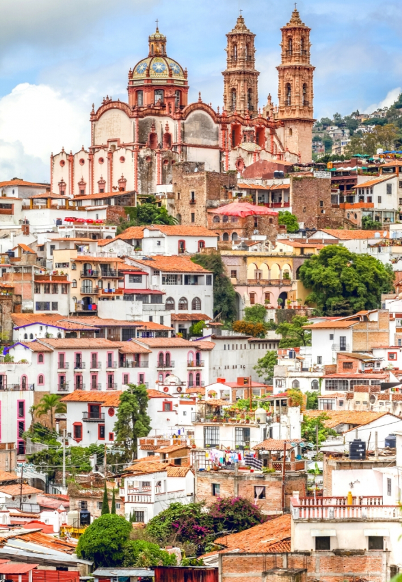 Terracotta rooftops and twin steeples of a grand cathedral rising above a hillside town, a signature of Mexico's unique colonial architecture.
