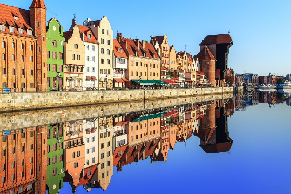 Reflective waterfront view of colorful buildings in Gdansk, showcasing the charm of living in Poland.