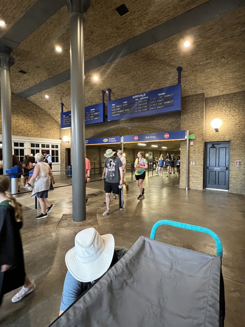 Busy arrival terminal with visitors pulling suitcases with hotel guests strategizing to use their Universal Express Pass for skipping lines at the theme park.