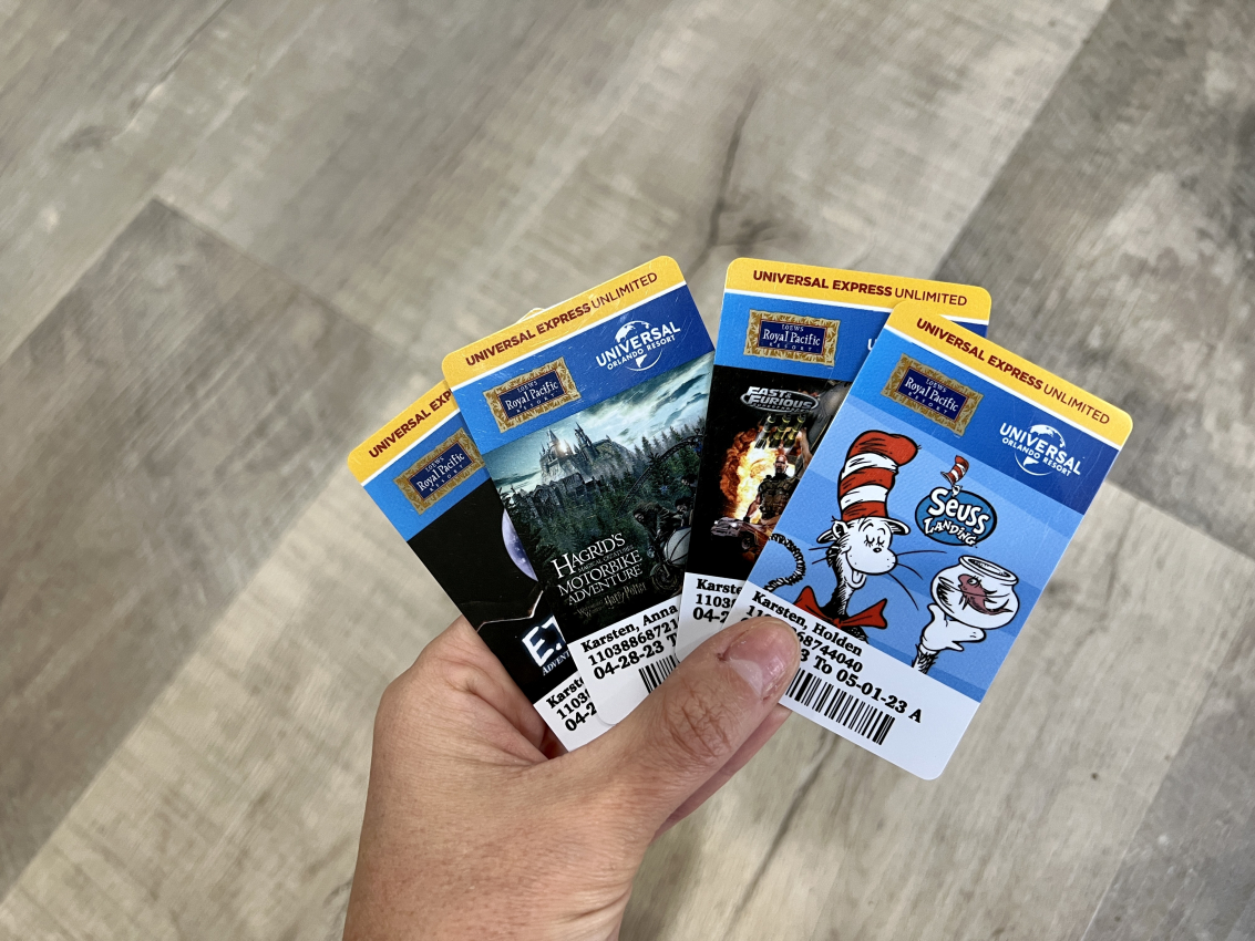 Hand holding a collection of Universal Express Unlimited passes featuring attractions, a savvy trick for hotel guests to maximize their time at Universal Studios.