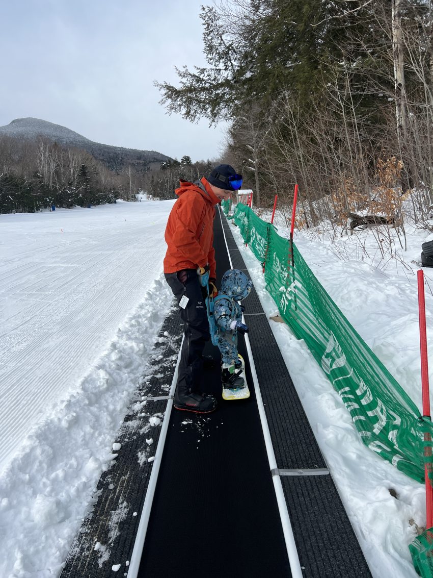 Toddler riding magic carpet on snowboard